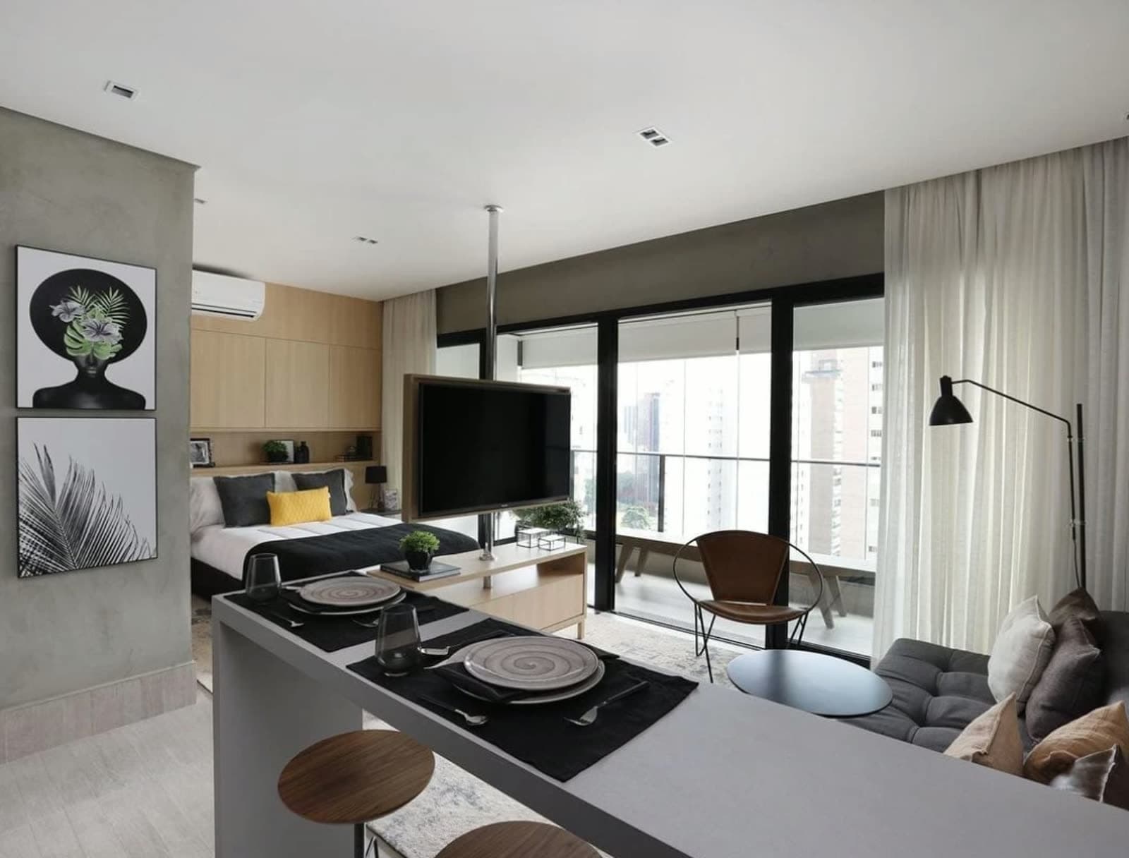 Sala de studio decorado com porta de vidro para a varanda e vista para a cidade