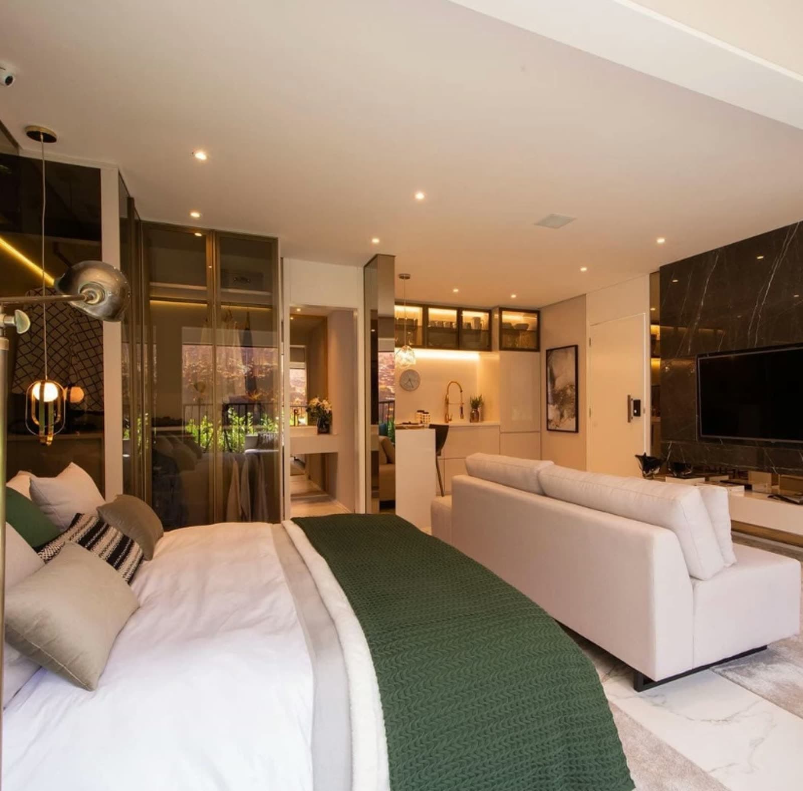 Studio decorado com cama, sala de estar integrada e iluminação embutida
