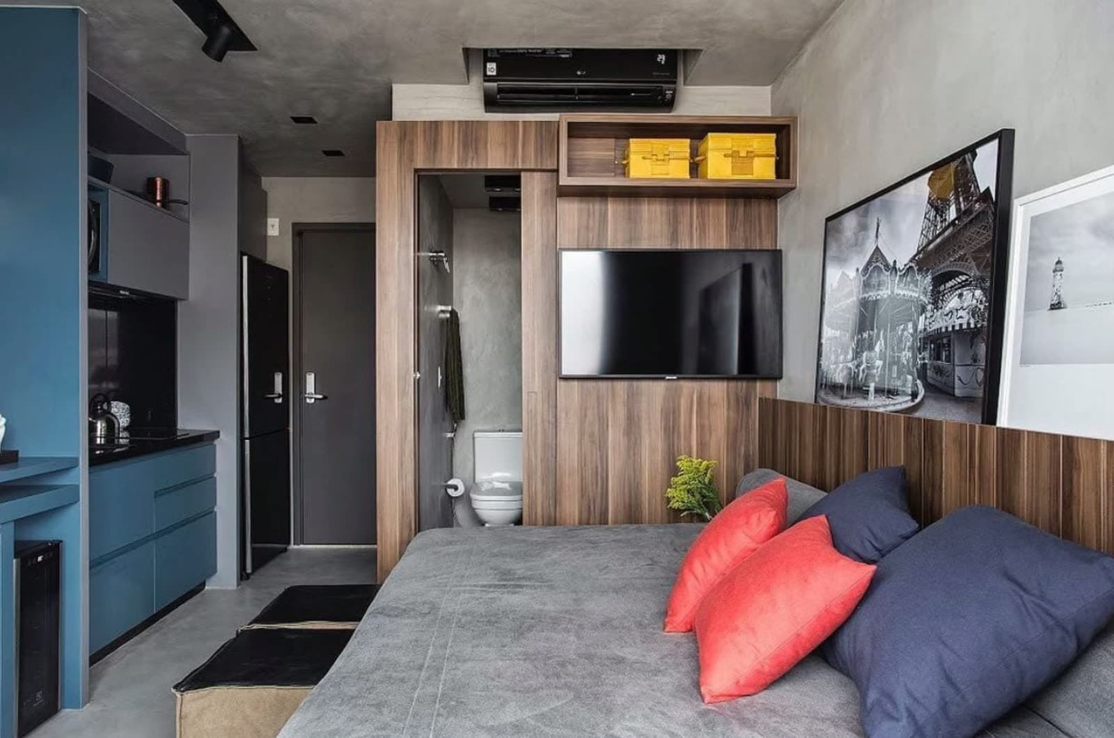 Studio compacto decorado com sofá, televisão, cozinha e área de banho integradas