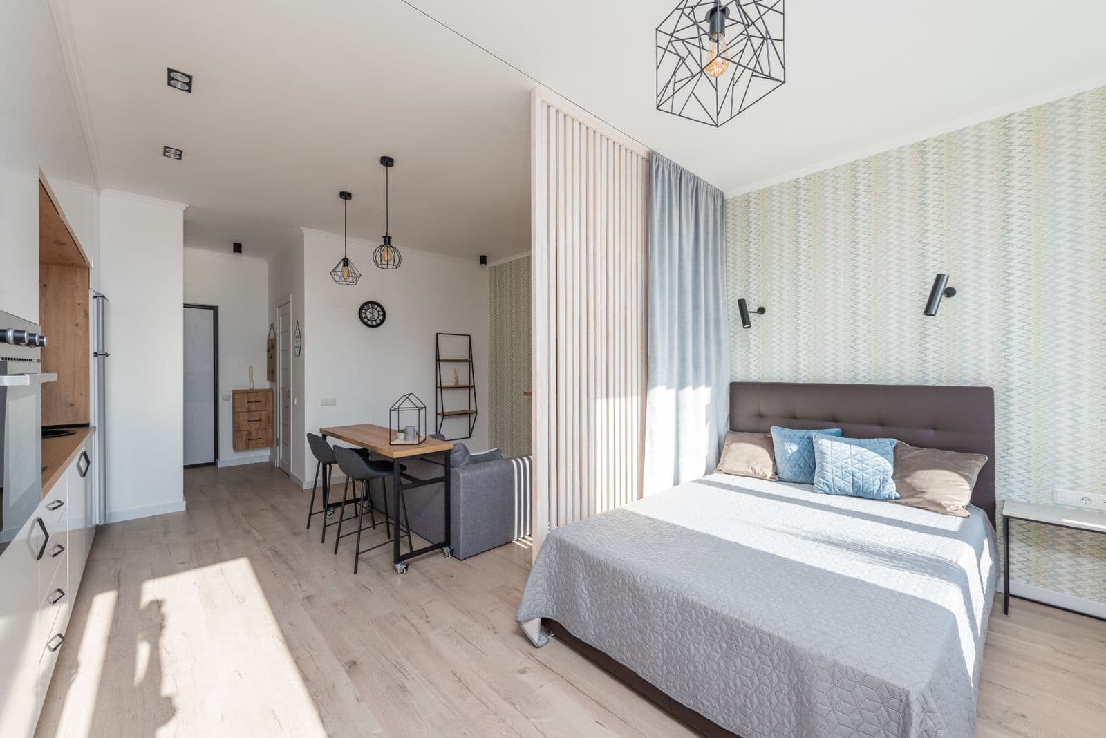 Studio compacto decorado, com cama, cozinha integrada e mesa de jantar