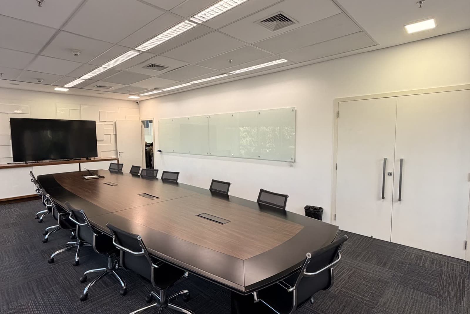 Sala de reunião da sede da Midrah, com mesa de reunião e televisão de apresentação