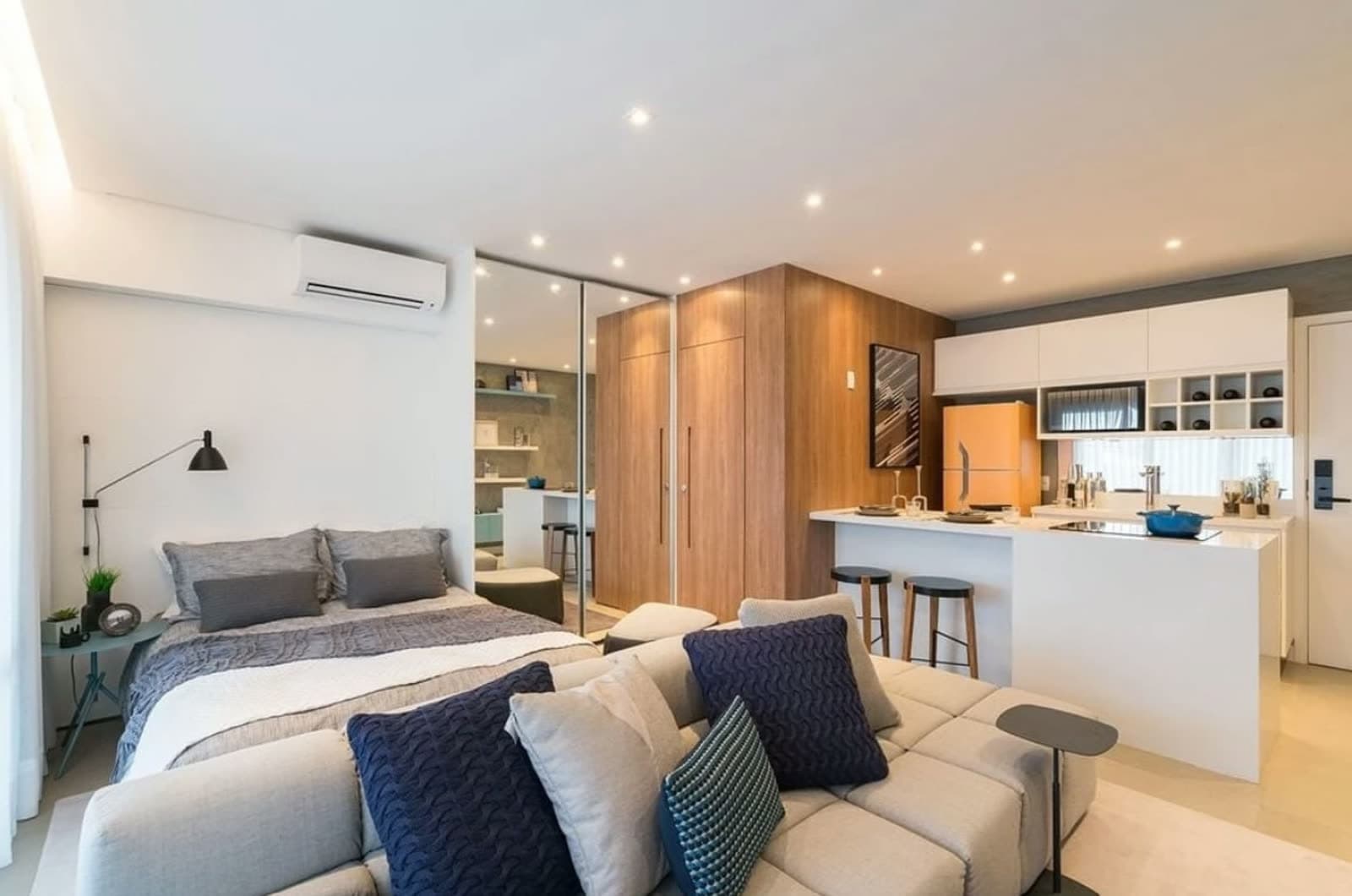 Studio decorado com cama, sofá e cozinha integrada, preparado para locação por temporada